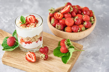 Strawberry granola or smoothie in glass and fresh berries in a wooden bowl. Healthy breakfast