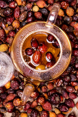 Glass Teapot of Herbal Dog Rose Tea With Dried Rosehips, Types Rosa Canina Hips Hot Drink of Medicinal Plants and Herbs Wooden background Top View
