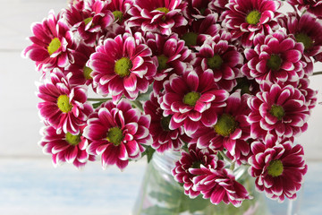 Bouquet of autumn flowers of pink chrysanthemums in a jug on a light wooden background. close-up
