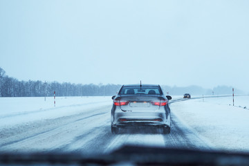 Fototapeta na wymiar Back view of car on snowy winter road