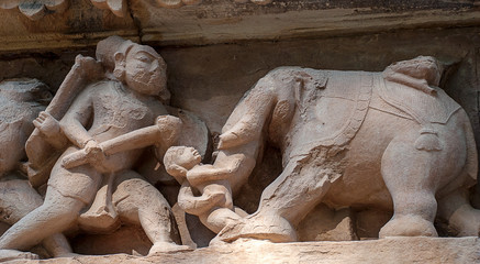 Fototapeta na wymiar Erotic sculptures on the walls of famous Khajuraho Temples in India. Khajuraho Temples are one of the UNESCO World Heritage Sites in India. The temples are famous for their Nagara-style architectural 