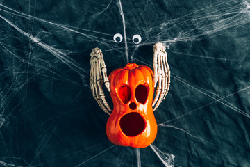Halloween background, pumpkins with eyes and mouths cut out, Bony hands hugging a pumpkin ,Jack lamp, gloomy and dark atmosphere, stretched web in the background