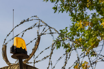 Razor wire and orange beacon on the fence. Protected area. Forbidden zone. Private territory....