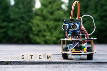Hand made robot working on the electronic platform. Natural background. Free space for text. STEM education for children and teenagers, robotics and electronics. DIY. AI. STEAM.