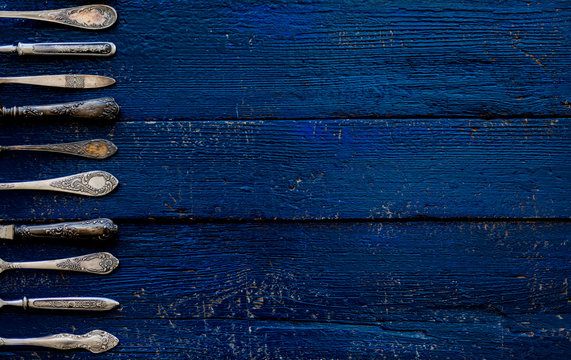 Vintage cutlery - spoons, forks and knives on an old wooden background.