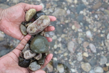 in hands showing some rocks or stones water Flowing Over Smooth Stones