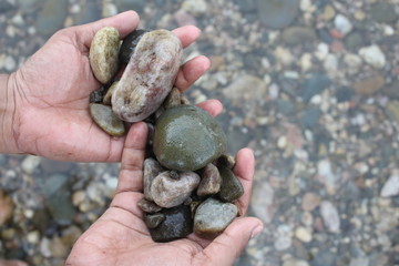 in hands showing some rocks or stones water Flowing Over Smooth Stones