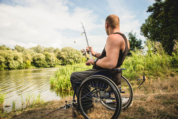 Handicapped man fishing at a lake. Wheelchair. Camping.
