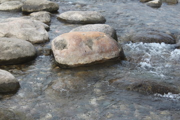 Fototapeta na wymiar water Flowing Over Smooth Stones