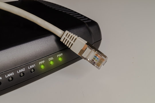 Black dsl modem or router with a network cable on a table. Concept picture for internet, wlan or mobil connections.