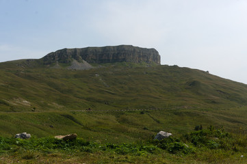 Gumbashi pass view of a huge rock in the russian caucasus, green meadow landscape at an altitude of...