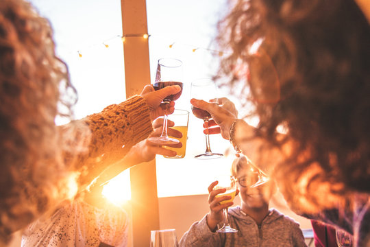 Greetings with family and friends, group of people enjoying evening drinks at end summer sunset. Hands that hold various glasses. Concept of vacation, carefree, relaxation, celebration and well-being.