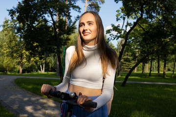 Fototapeta na wymiar Portrait of a smiling girl after riding an electric scooter in the park