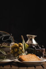 Green and black olives and bread and oilcan vertical view
