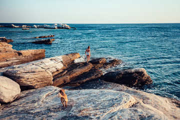 Girl and her dog exploring rocky beach