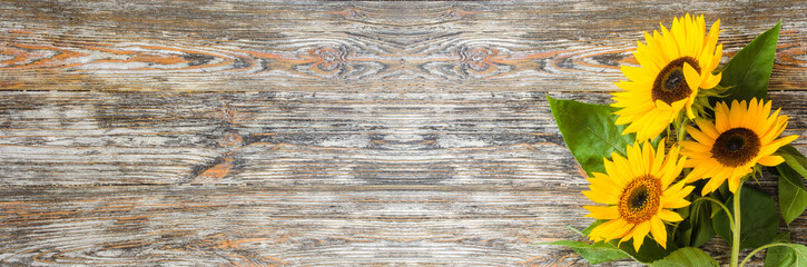 Autumn banner with a bouquet of yellow sunflowers on vintage textured wooden background.