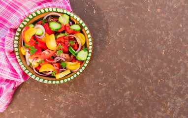 Salad of tomato, pepper, cucumber, onion, herbs. Homemade food. The concept of tasty and healthy food. Dark brown background. Top view. Copy space.