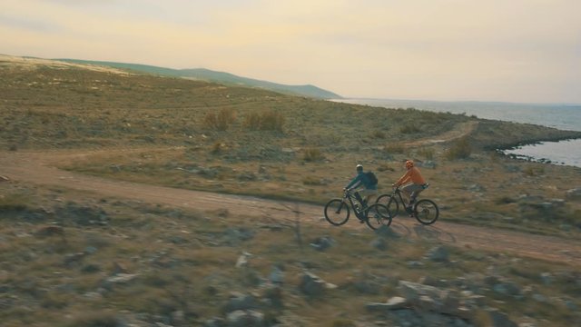 Tracking shot of twp guys riding bikes at sunset