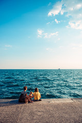 Mother and daughter sitting on the waterfront with dog