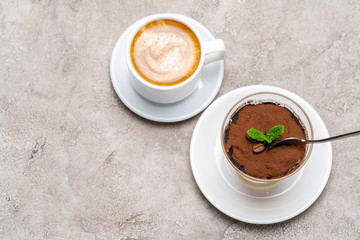 Portion of Classic tiramisu dessert in a glass cup and espresso coffee on concrete background