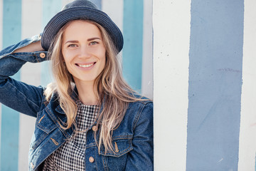 Happy pacified young woman in summer clothes sitting in urban space against a background of blue...