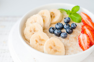 Oatmeal with bananas, strawberries, nuts and blueberries. Healthy breakfast.