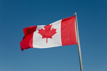 Canadian flag waving against blue sky