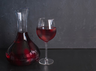 Decanter with red wine and a glass on a black background. Free space for text. Copy space
