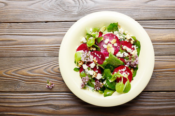 Top view at mediterranean roasted beet salad with walnuts feta cheese oregano and mash leaves on wooden table