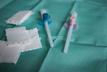 Zwei Infusionskanülen neben Tupfer auf sterilem Tuch bereit