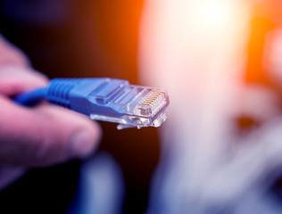 Technician connecting network cables to switches. Connecting cables in server cabinet.