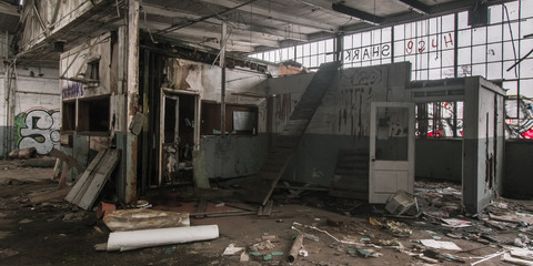 Abandoned, dilapidated Detroit factory with a disintegrating interior, graffiti-covered grass and a dirt-covered floor