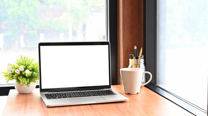 Fototapeta premium Mockup laptop computer on wooden table in cafe co working space.