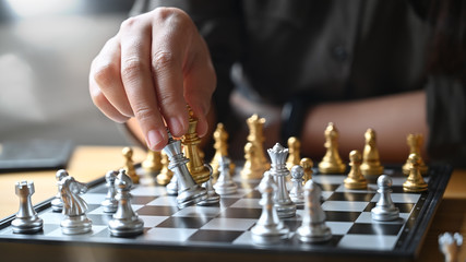 Strategy or leadership concept, Hand of business moving chess figure in competition success with closeup shot.