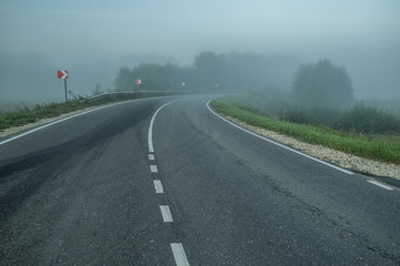 Big road with signs and morning fog