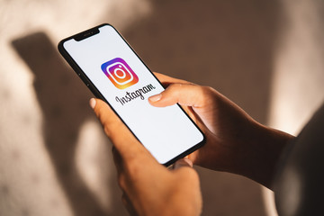BERLIN, GERMANY JULY 2019: Woman hand holding iphone Xs with logo of instagram application. Instagram is largest and most popular photograph social networking.