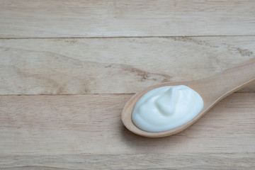 Natural homemade plain organic yogurt in wooden wood spoon on wood texture background