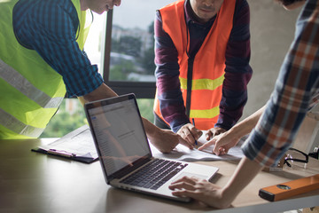 team of engineer planing and working with laptop and blue print on working table in construction...