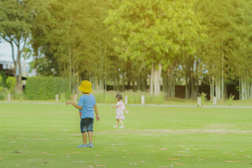 A little boy in a blue shirt enjoys a relaxing time playing on the green lawn at the public park in the evening.