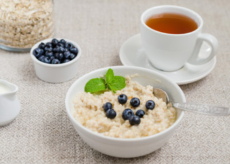 Healthy breakfast. porridge in a bowl with honey and berries and tea. Close-up