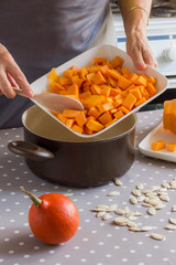 Preparation of products for making pumpkin soup. Female hands put chopped pumpkin in a pan. Gray Polka Dot Tablecloth
