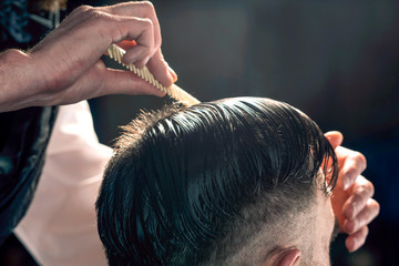 Hairdresser performs a haircut to a man, close-up.