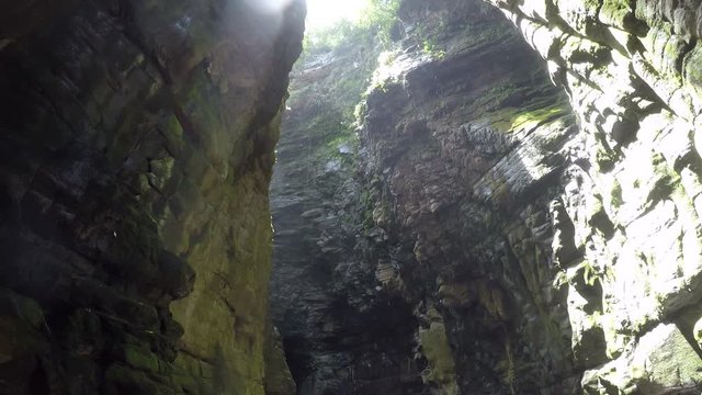 A cave in Canaima national park in Venezuela, with a big hole in the roof and water drops dropping down.