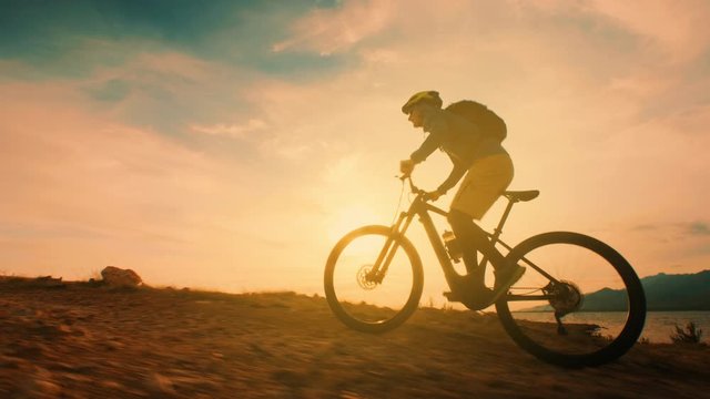 Low angle shot of a man cycling at sunset