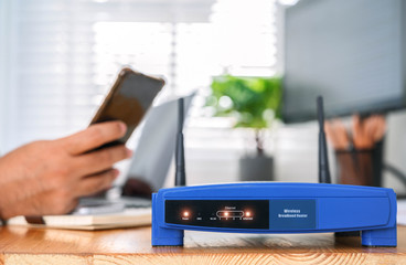 closeup of a wireless router and a man using smartphone on living room at home ofiice