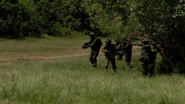 A group of masked military soldiers moving through the forest, the operation to release the hostages, the unit is put forward in the given coordinates