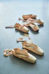 Old faceless pointe shoes on the floor. Female ballet footwear on grey background. Clothing items for ballet dancers.