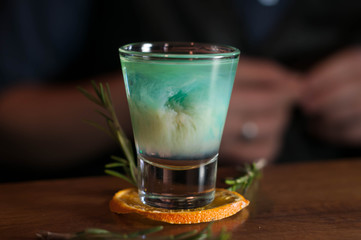 selective focus of blue alcohol cocktail in glass on orange slice and wooden bar counter in restaurant