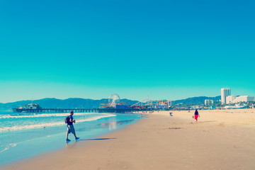 Fototapeta na wymiar Photographer walking in world famous Santa Monica beach