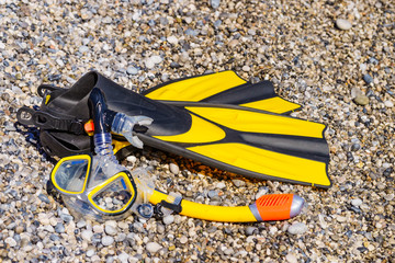 Flippers and snorkeling tube on sea shore
